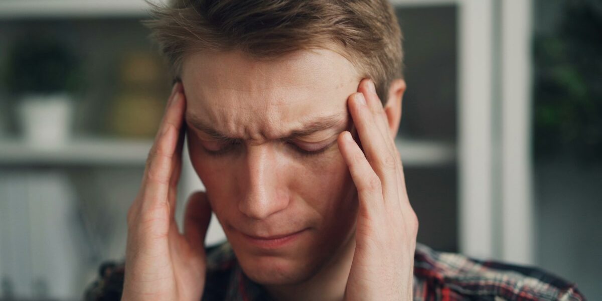 Man holding his temples during a migraine headache